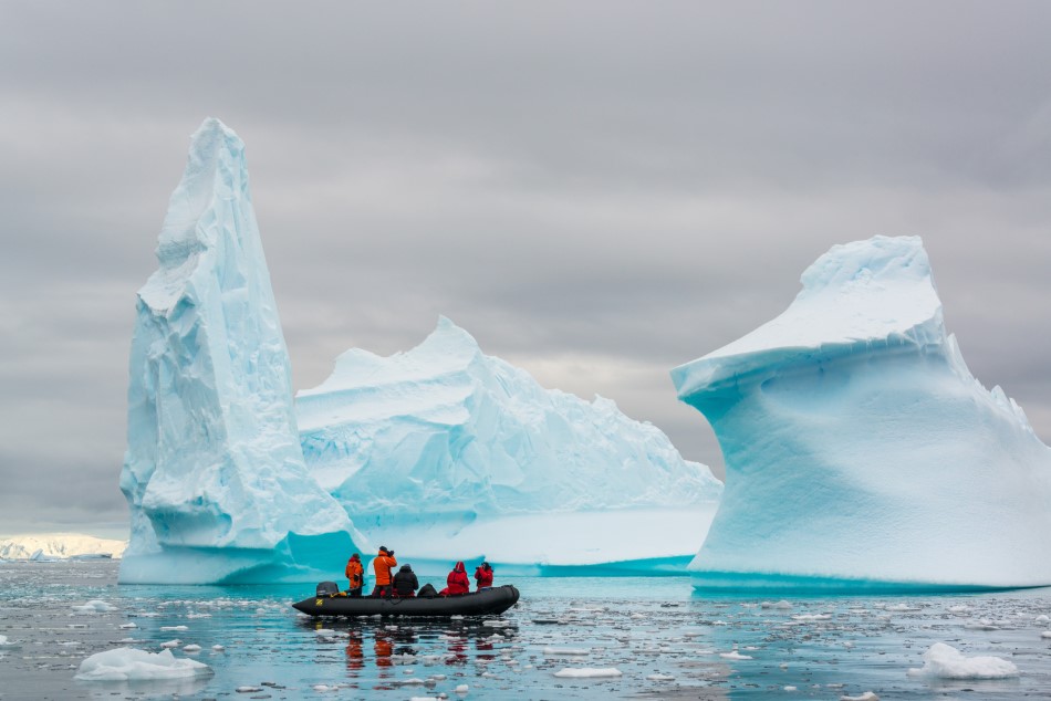People photographing large icebergs in the Southern Ocean, also known as the Antarctic Ocean.